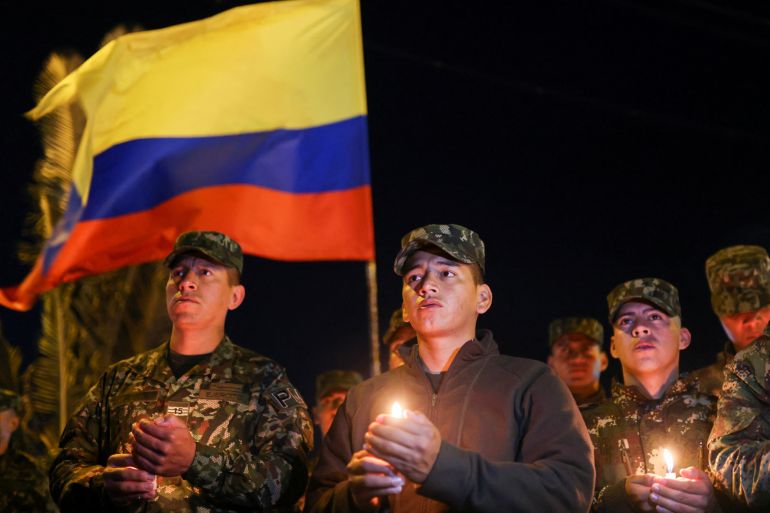 Soldiers hold candles as Colombian flag flies in background