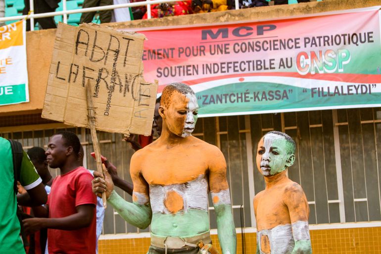 A supporter of Niger's coup leaders holds a sign reading "Knock down France" during a rally at a stadium in Niamey, Niger, August 6, 2023.