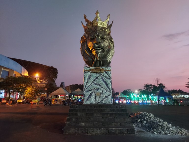 A statue of a lion at the Kanjuruhan stadium at dusk