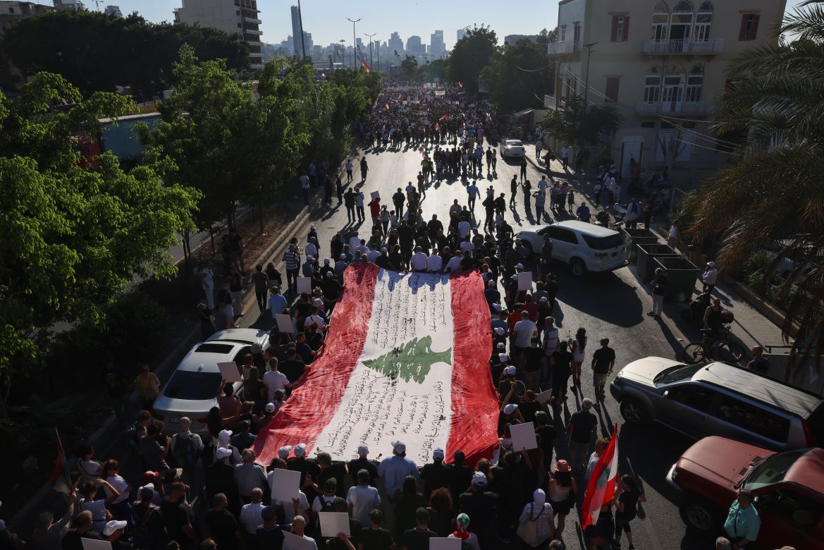 Protesters lift flags and placards depicting the victims of the 2020 Beirut port blast