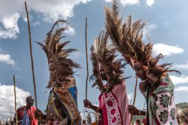Young Maasai men wearing a ceremonial headdress made of ostrich feathers parade at the ceremonial site during the Eunoto ceremony