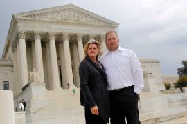 A couple stands in front of the Supreme Court on a cloudy day.