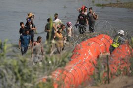Migrants face barbed wire in the Rio Grande river