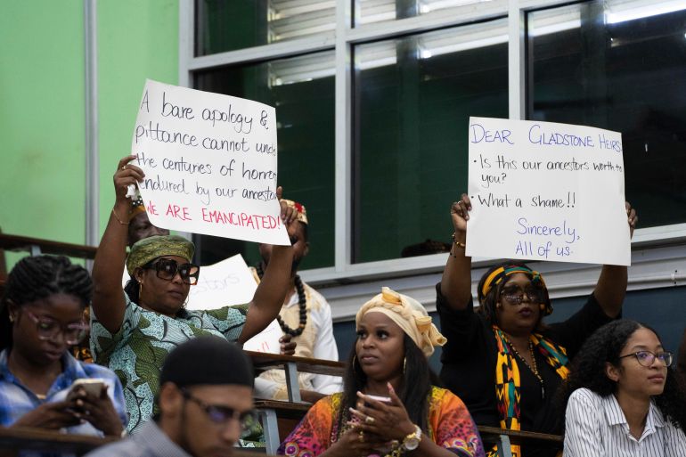 People hold up messages during a speech by Charles Gladstone in Guyana