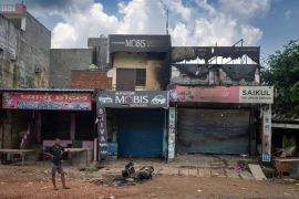 A man stands next to partially burned shops in Sohna near Nuh in Haryana state, India