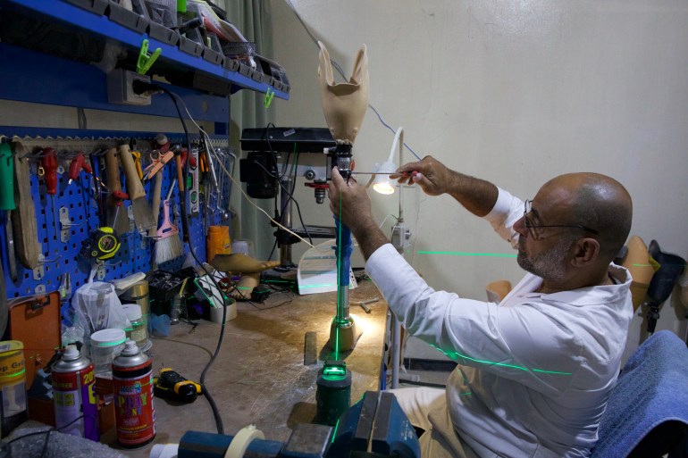 A technician working on a prosthetic leg on a workbench
