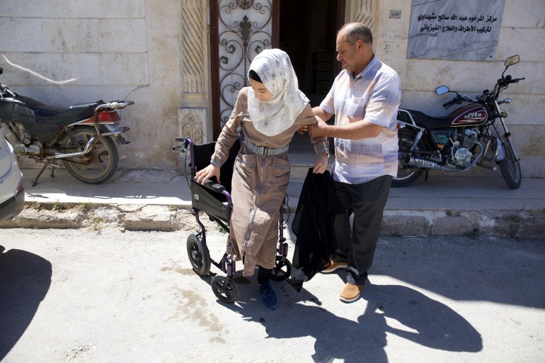 Rima is helped out of her wheelchair by her uncle