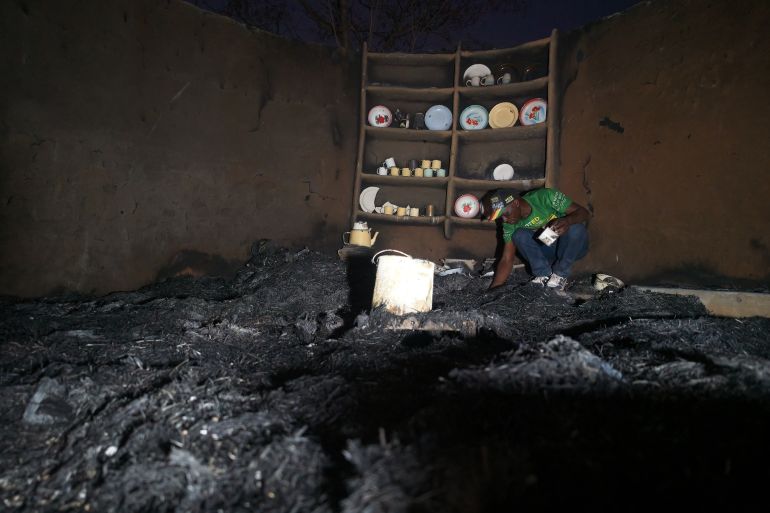 Shepherd Mahove, 48, looks through the ashes of his burnt kitchen at his homestead in Hanke B Village, Zimbabwe