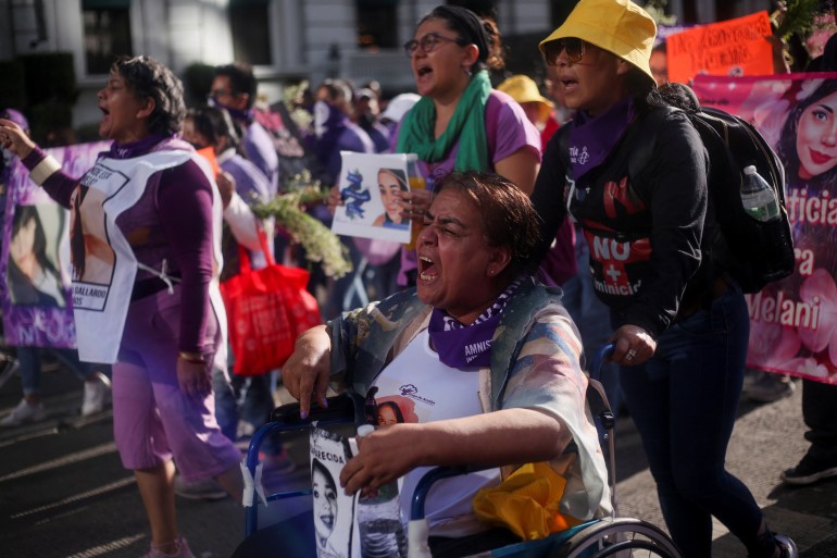 Demonstrators carry photos of missing girls and women during a march in Mexico City against gender-based violence. Many are also wearing green and purple, symbols of the movement.