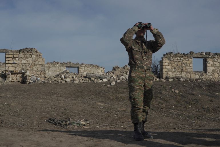 An Armenian soldier looks through binoculars at a fighting position in Nagorno-Karabakh in January 2021