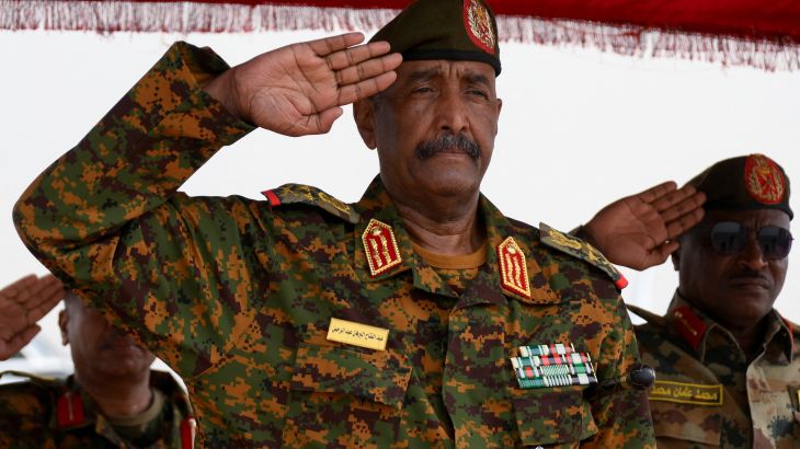 Sudan's General Abdel Fattah al-Burhan salutes as he listens to the national anthem after landing in the military airport of Port Sudan
