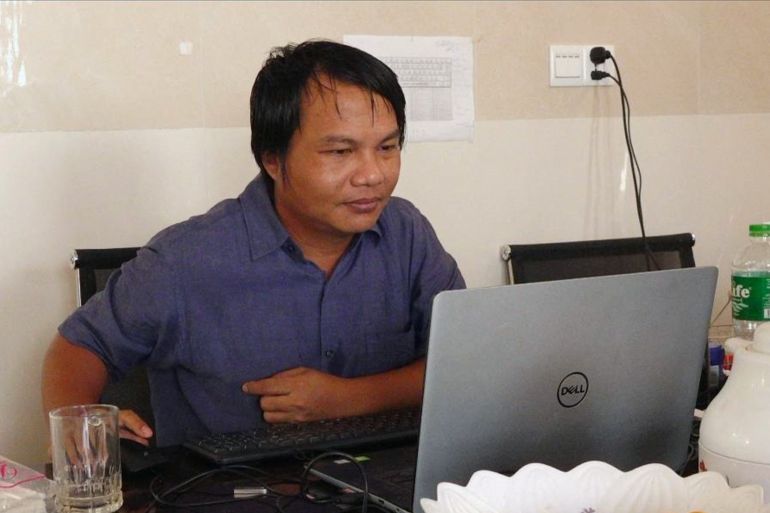Myanmar photojournalist Sai Zaw Thaike is seen working at his laptop. He is sitting at a desk.