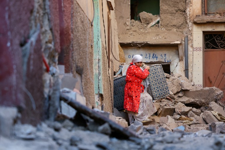 A woman carries belongings out of a damaged building, in the aftermath of a deadly earthquake in Moulay Brahim, Morocco, September 10, 2023. REUTERS/Hannah McKay TPX IMAGES OF THE DAY