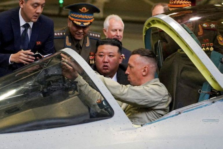 North Korean leader Kim Jong Un checking out a Russian fighter jet. The pilots in the cockpit and pointing things out to Kim