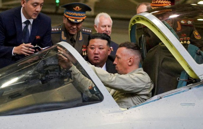 North Korean leader Kim Jong Un checking out a Russian fighter jet. The pilots in the cockpit and pointing things out to Kim