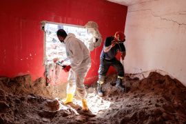 Libyan and Italian rescuers removes mud from a house searching for bodies in the aftermath of the floods in Derna