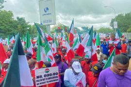 Members of the Nigerian Labour Congress, holding flags and placards, march during a protest against fuel price hikes and rising costs [File: Abraham Achirga/Reuters]