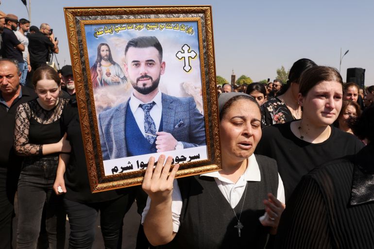 A mourner carries the portrait of a victim during the funeral of victims of the fatal fire at a wedding celebration, in Hamdaniya, Iraq, September 28, 2023