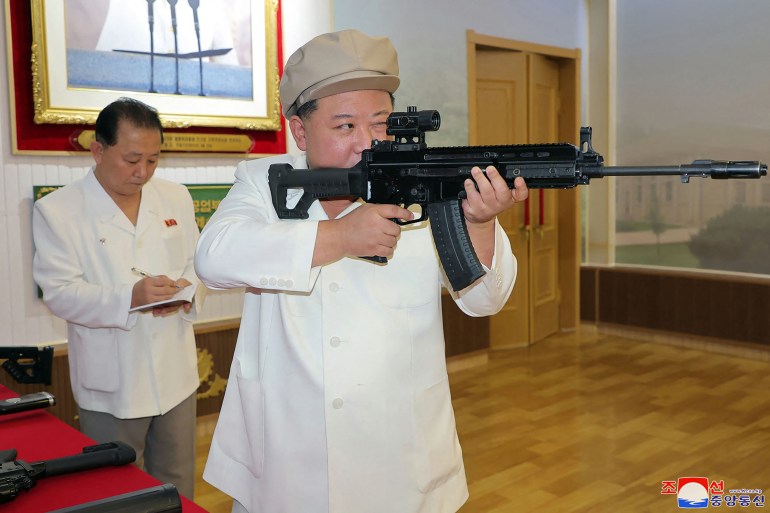 Kim Jong Un looking down a rifle sight in a picture released in August. Hie is wearing a white shirt and beige cap. 