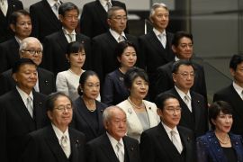 Japanese Prime Minister Fumio Kishida standing with his new cabinet ministers