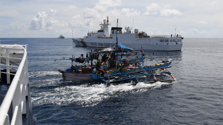 This photo taken on September 22, 2023 shows Philippine fishing motherboat "Moises" (C) sailing past a Chinese coast guard ship (background) after the former was blocked from sailing near the Chinese-controlled Scarborough Shoal in disputed waters of the South China Sea. China, which claims sovereignty over almost the entire South China Sea, snatched control of Scarborough Shoal from the Philippines in 2012. Since then, it has deployed coast guard and other vessels to block or restrict access to the fishing ground that has been tapped by generations of Filipinos. (Photo by Ted ALJIBE / AFP)