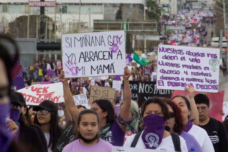 Women hold signs against gender-based violence and in favor of abortion on International Women's Day, in Chihuahua, Mexico, Wednesday, March 8, 2023. A