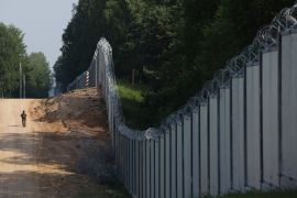 File: A Polish border guard patrols the area of a built metal wall on the border between Poland and Belarus, near Kuznice, Poland, on June 30, 2022. [Michal Dyjuk/AP Photo]