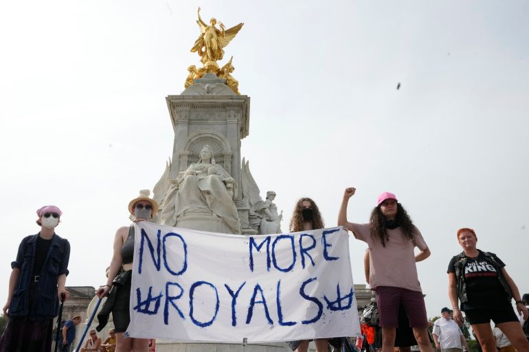 Anti Royal demonstrators stand on the Queen Victoria Memorial on the First anniversary of the death of Britain's Queen Elizabeth II, at Buckingham Palace, in London, Friday, Sept. 8, 2023. With gun salutes and tolling bells, Britain is marking the first anniversary of the death of Queen Elizabeth II and the ascension of King Charles III, who remembered his mother as a symbol of stability during her 70-year reign. (AP Photo/Kirsty Wigglesworth)