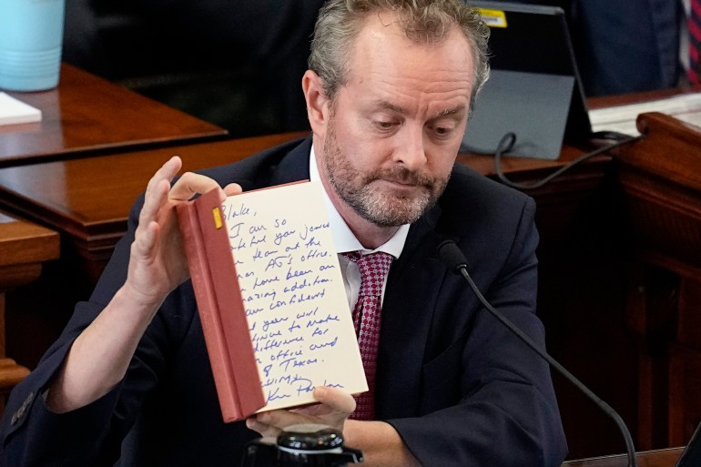 Whistleblower Blake Brickman shows a book with an inscription from Texas Attorney General Ken Paxton as he testifies during the impeachment trial for Paxton in the Senate Chamber at the Texas Capitol, Wednesday, Sept. 13, 2023, in Austin, Texas.