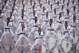 South Korean soldiers give a demonstration of their skills in the traditional Korean martial art of Taekwondo. They are wearing white outfits with black belts.