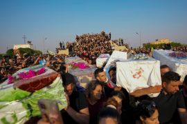 Crowd in funeral procession holding up coffins