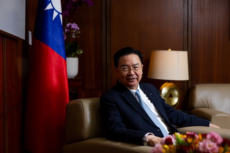 A portrait of Joseph Wu in his office in Taipei. There is flag behind him.