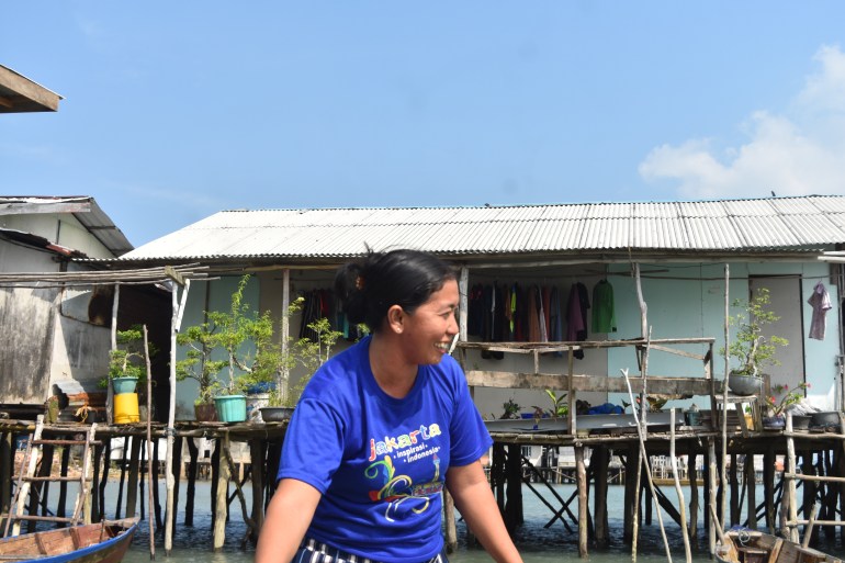 A rempang resident looking out over the water. There is a wooden house behind her, built on stilts over the water