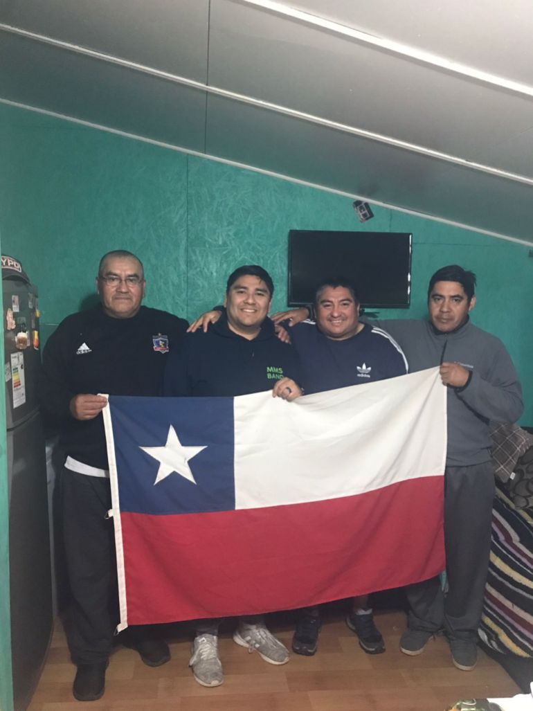 Four brothers hold up a Chilean flag at a reunion.