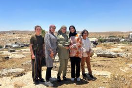 Five young girls who just finished playing on Khirbet Susiya’s playground stand triumphantly in front of their village. [Theia Chatelle/Al Jazeera]