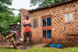 Joachim Kyibabu stands outside his home in Busamba village, Wakiso, Uganda on April 14, 2023 [Isaac Kasamani/Al Jazeera]