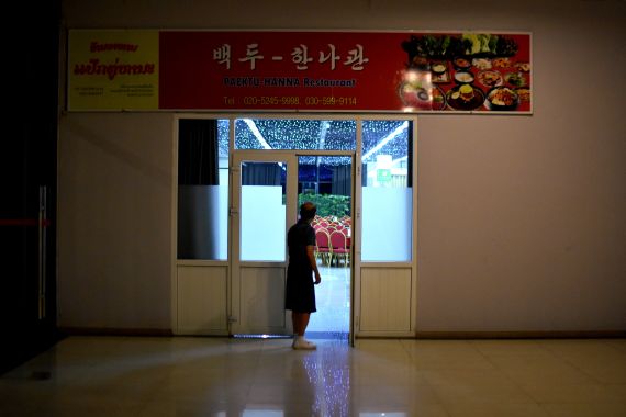Someone peering into the empty Paektu North Korean restaurant in Vientiane. The lights are all on but it's very quiet.