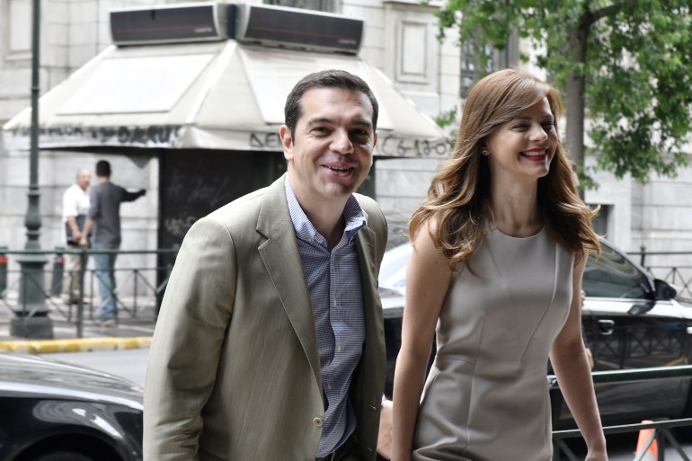 Greek prime minister Alexis Tsipras (L) smiles, while he arrives for his meeting with Greek Labour Minister Efi Achtsioglou (R) at the labour ministry in central Athens on July 17, 2017. Bolstered by its third bailout programme and positive reports from the European Union, Greece is planning an imminent test of the bond market, local media said this weekend. (Photo by LOUISA GOULIAMAKI / AFP)