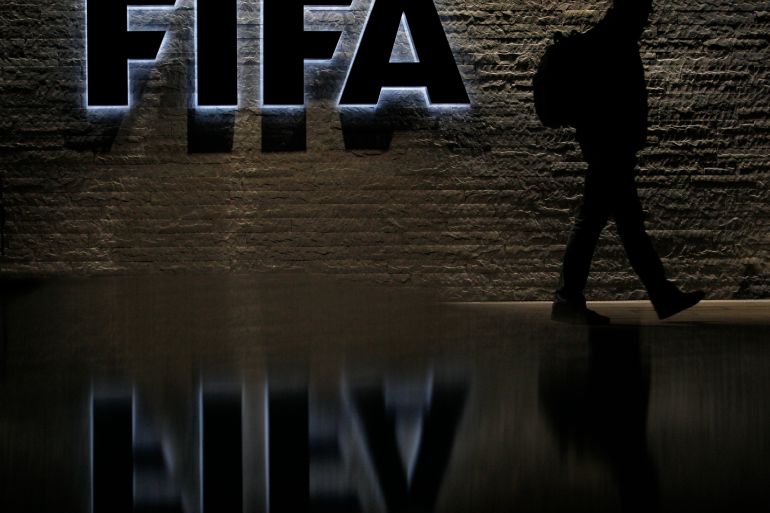A man is silhouetted as he makes his way past the main entrance of FIFA headquarters.