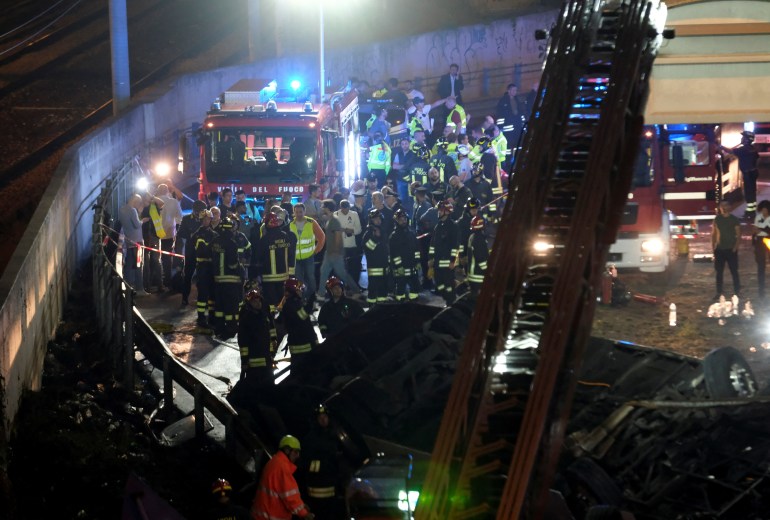 Firefighters and rescue personnel work near a bus after it crashed off an overpass in Mestre