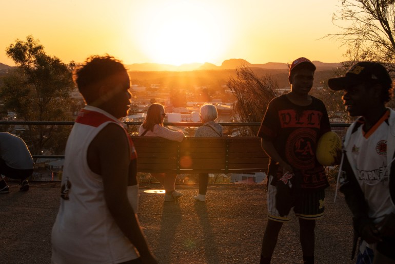 Aboriginal boys play as people watch the sunset over Alice Springs