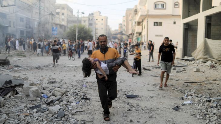 A Palestinian man carries a wounded girl at the site of Israeli strikes, in Khan Younis in the southern Gaza