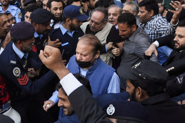Pakistan's former Prime Minister Nawaz Sharif walks with party workers and police officers as he leaves after appearing at the Islamabad High Court, in Islamabad
