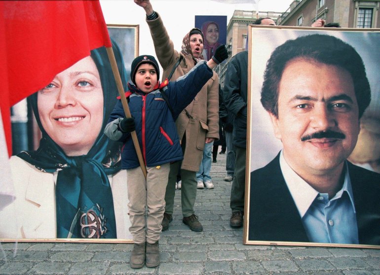 A young Iranian child shouts slogans standing in front of a portrait of Maryam Rajavi (L) and Masoud Rajavi (R), leaders of the National Council of Resistance of Iran
