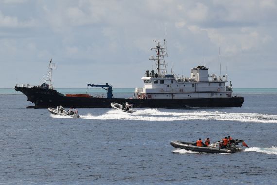 Chinese coast guard personnel aboard rigid hull inflatable boats sailing near a Chinese maritime militia vessel at Scarborough Shoal