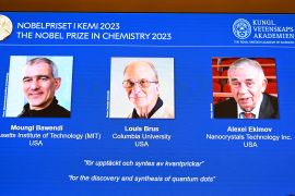 Pictures of American chemists Moungi Bawendi and Louis Brus and Russian physicist Alexei Ekimov appear on a screen during the announcement of the winners of the 2023 Nobel Prize in Chemistry in Stockholm, Sweden