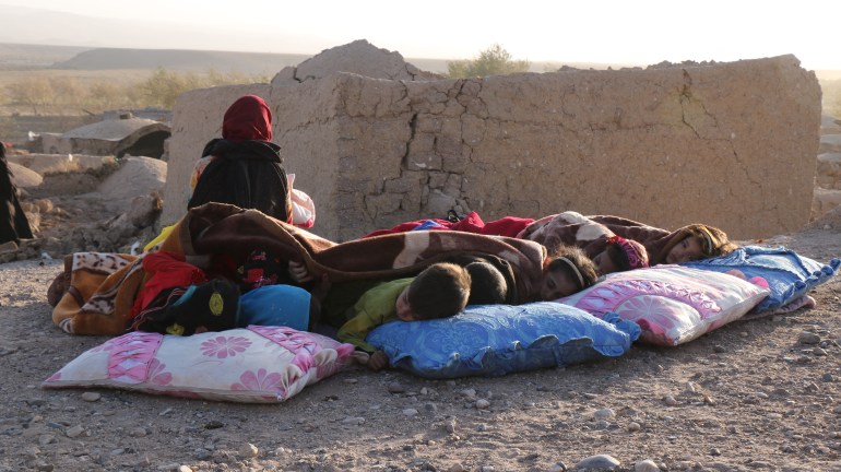 Afghan children rest under a blanket beside damaged houses after earthquake in Sarbuland village of Zendeh Jan district of Herat province on October 7,2023
