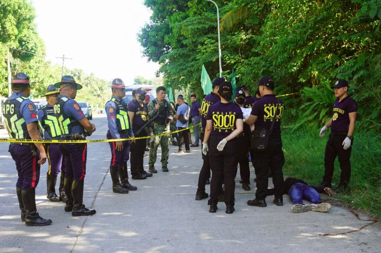 Police gather evidence beside bodies at the scene of a shooting outside a polling station following a confrontation between supporters of rival candidates in Datu Odin Sinsuat town on Mindanao island