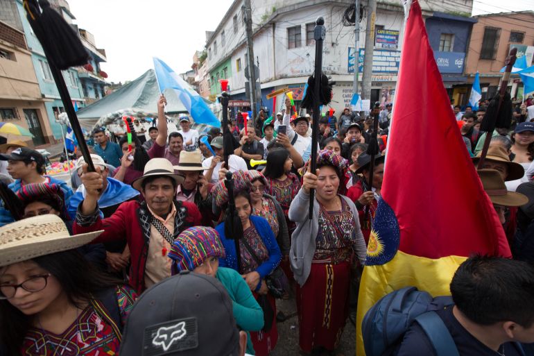 Raising staffs and flags into the air, Indigenous protesters march through the streets of Guatemala City.