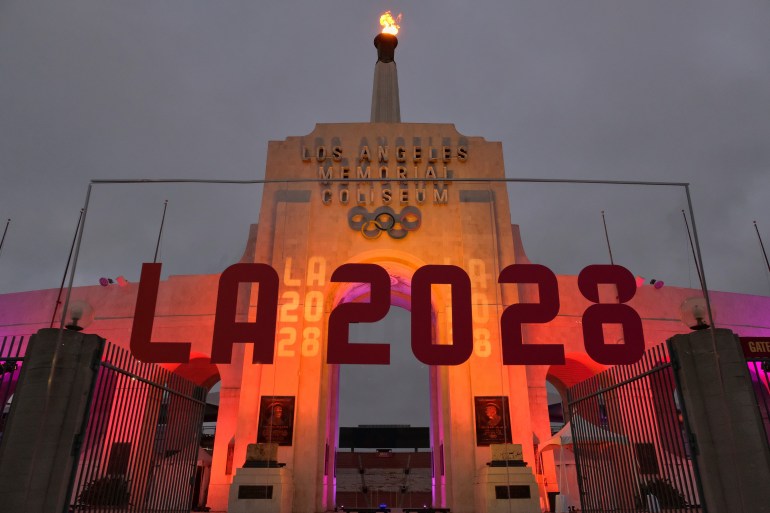An LA2028 sign is seen in front of a blazing Olympic cauldron at the Los Angeles Memorial Coliseum on Wednesday, Sept. 13, 2017. The cauldron was lit early Wednesday morning at the stadium that was the site of the 1932 and 1984 Olympics. An International Olympic Committee meeting in Peru is to make it official that LA will host in 2028 and that the 2024 Games will go to Paris. (AP Photo/Richard Vogel)